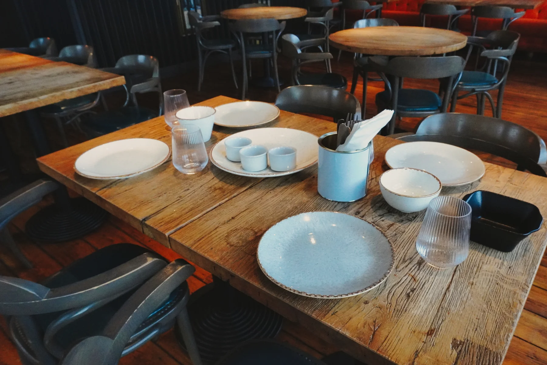 Wooden dining table laid with plates, cutlery and glasses