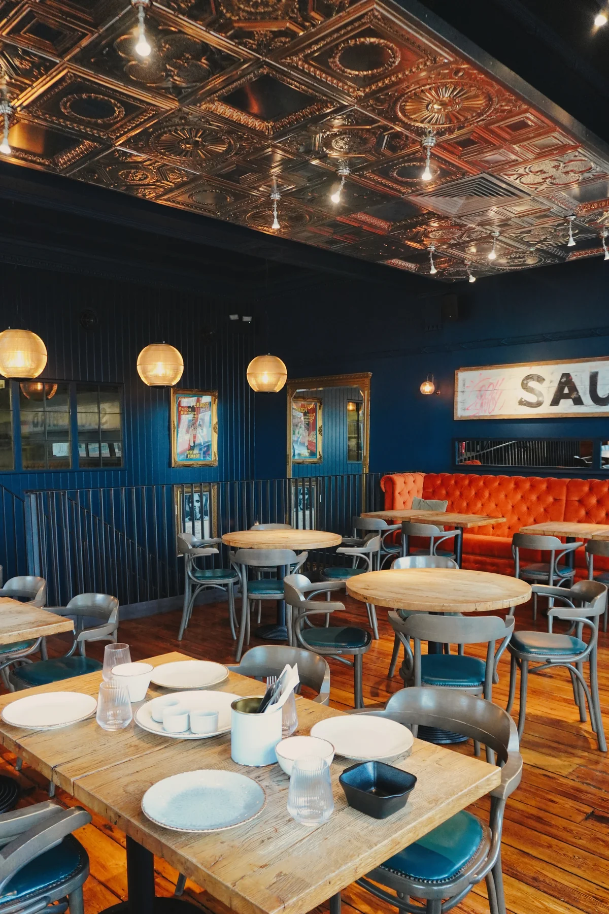 Wooden tables and chairs with the orange banquette in the background