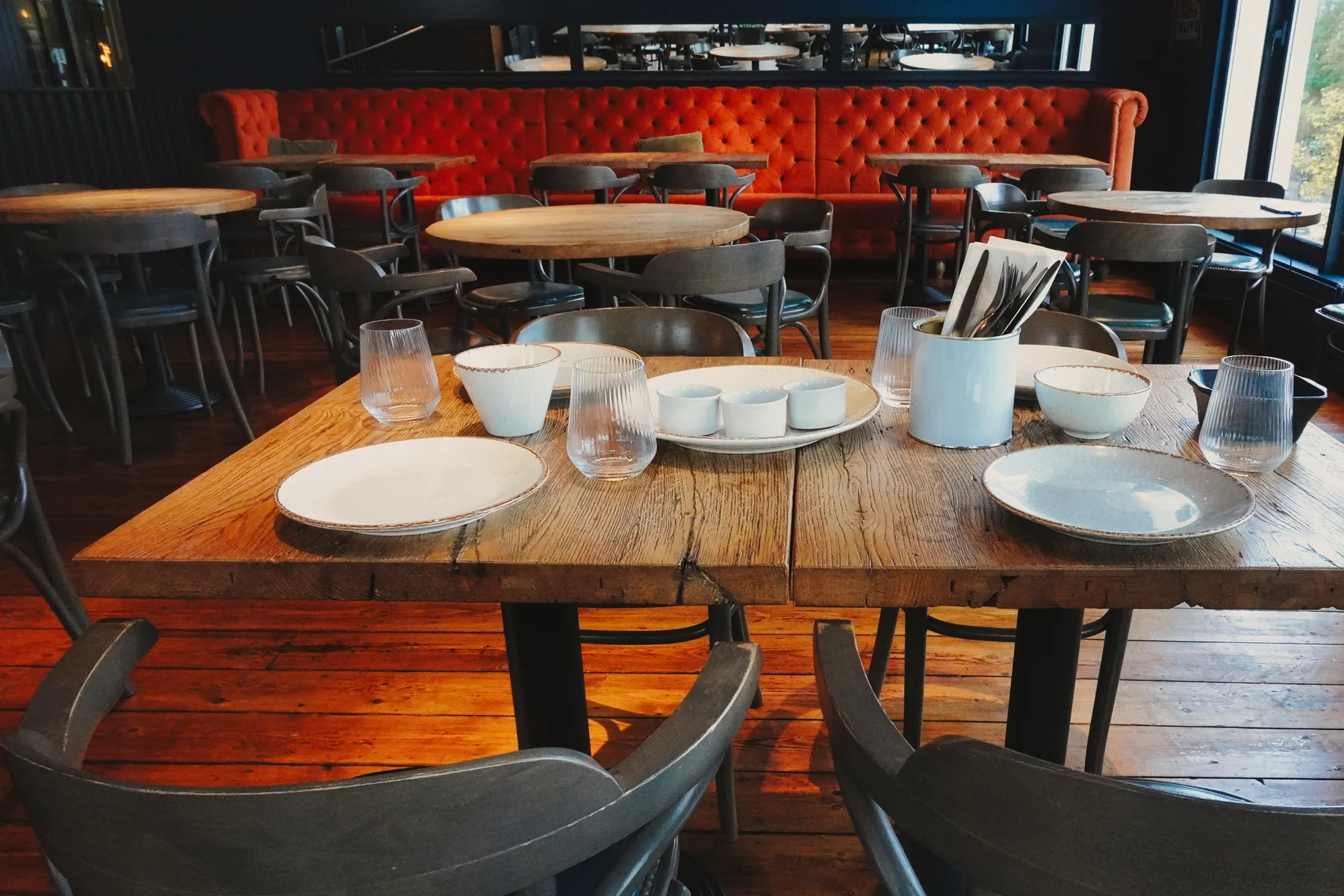 Set dining table with wooden chairs and orange banquette