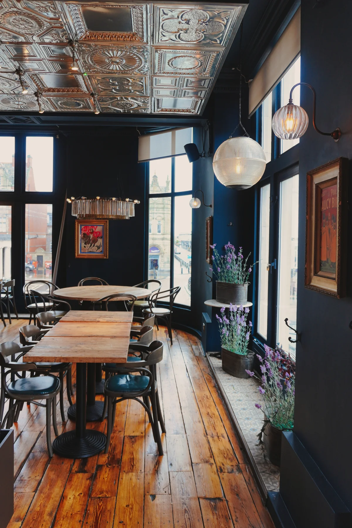 Dining tables beside globe wall lights and tall windows